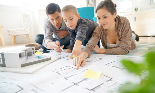 Family at home looking at future house blueprint and model Family at home looking at future house blueprint and model